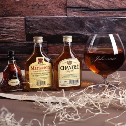 Cognac-Kollektion aus verschiedenen Weinbränden mit Weinbrandglas in gravierter Holzkiste