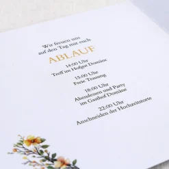 Einladungskarte zur Hochzeit mit Blütenkranz und rundem Anhänger