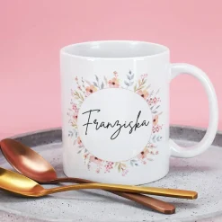 Weiße Keramiktasse mit Namensaufdruck und Blumenmotiv